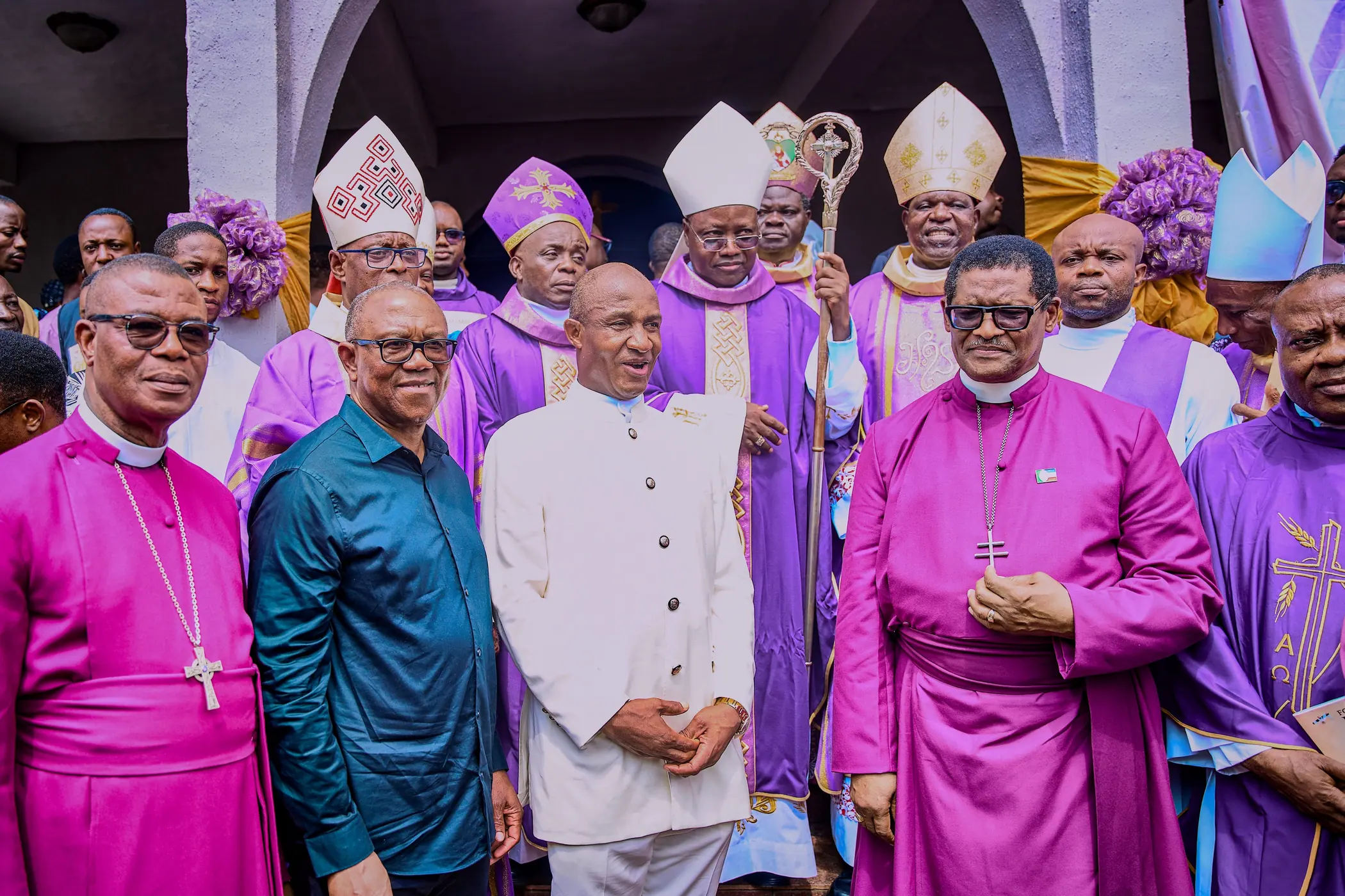 Peter Obi standing among bishops in purple cassocks and mitres inside a church