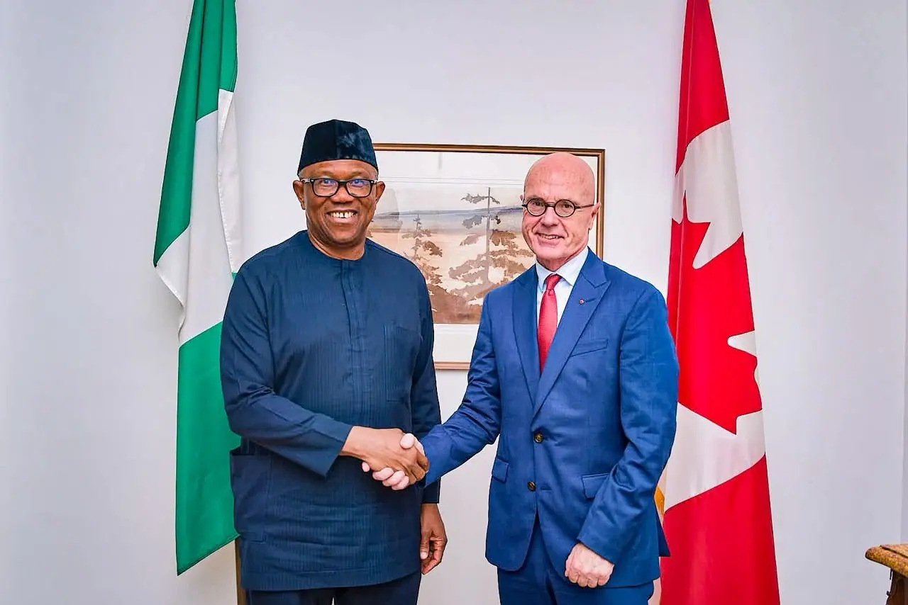 Peter Obi shaking hands with a diplomat between a Nigerian flag and a Canadian flag