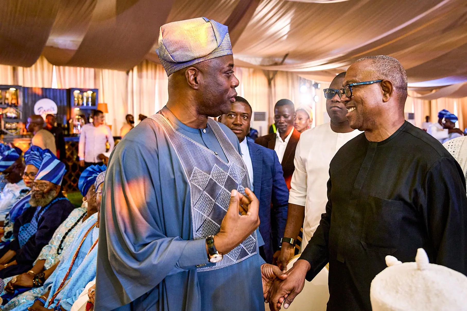 Peter Obi greeting Governor Seyi Makinde under a decorated canopy, elders seated behind