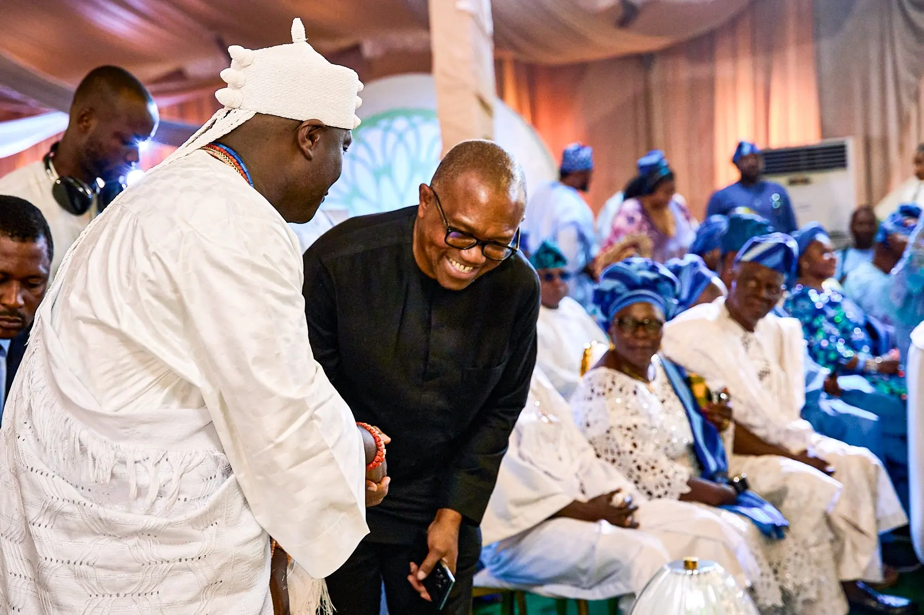Peter Obi leaning in to greet the Ooni of Ife, Oba Adeyeye Enitan Ogunwusi, in white ceremonial dress at a large gathering
