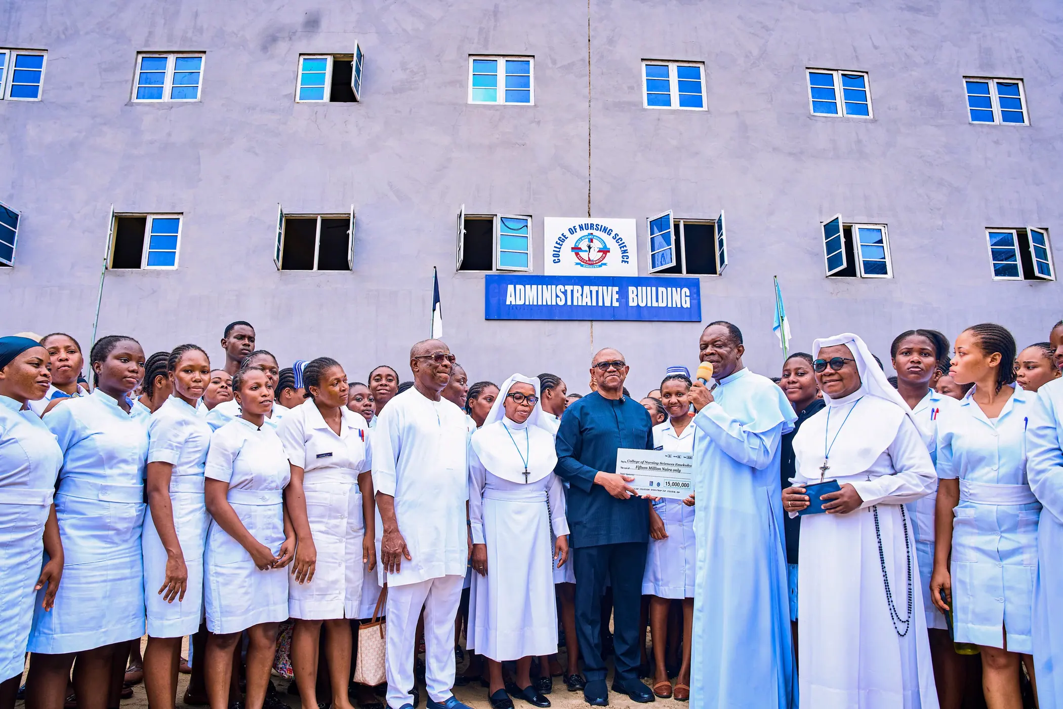 Peter Obi standing with nuns, nurses and students for a group photograph outside a college building