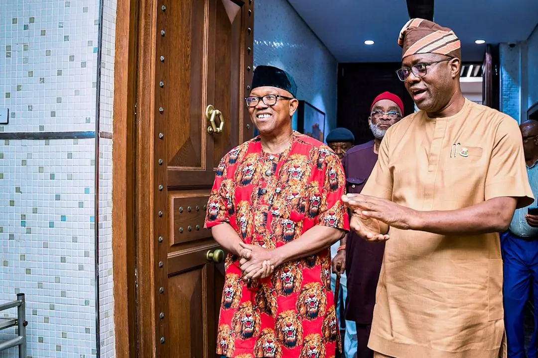 Peter Obi laughing with a host who is welcoming him through a doorway