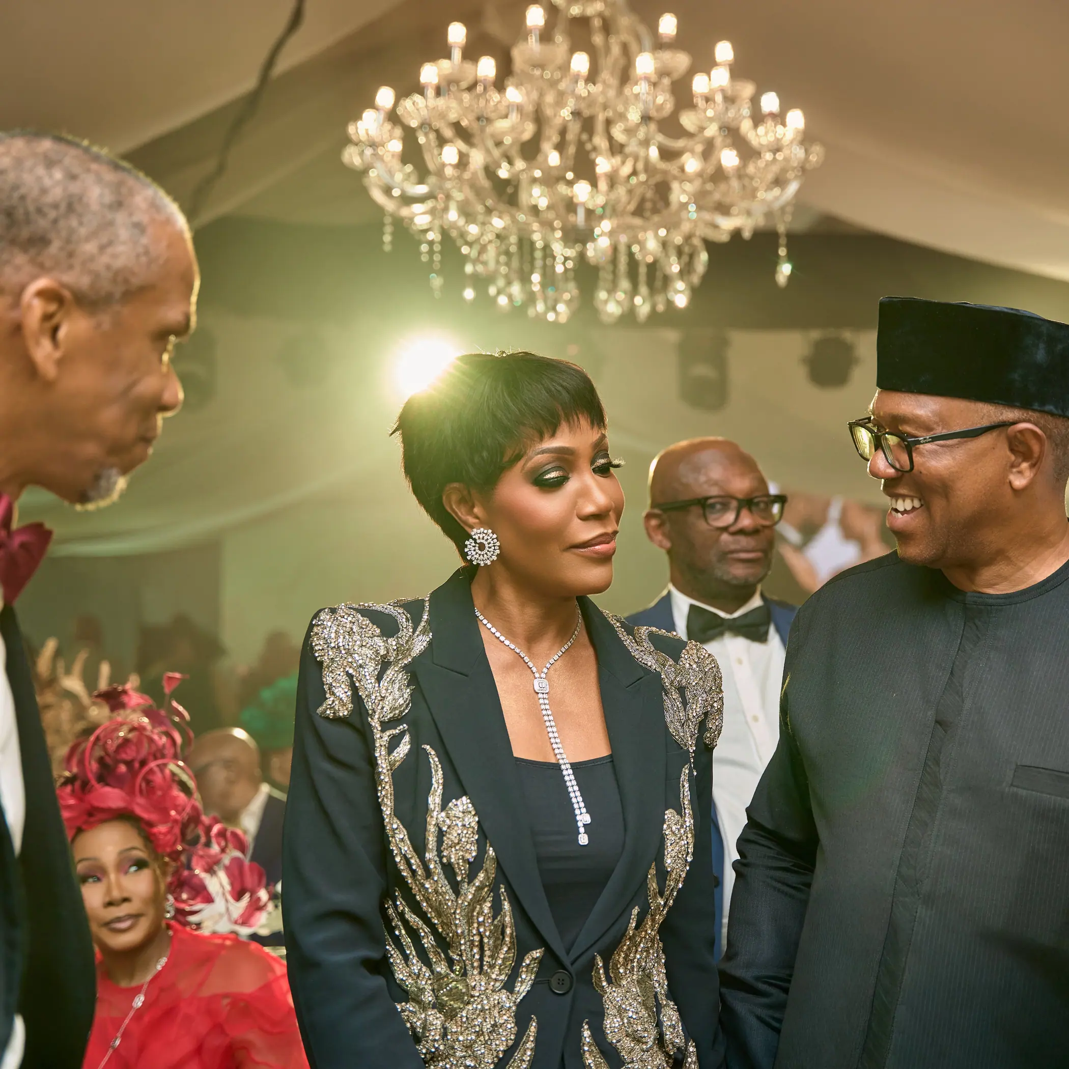 Peter Obi in conversation with his wife Margaret Obi at an evening reception under a chandelier