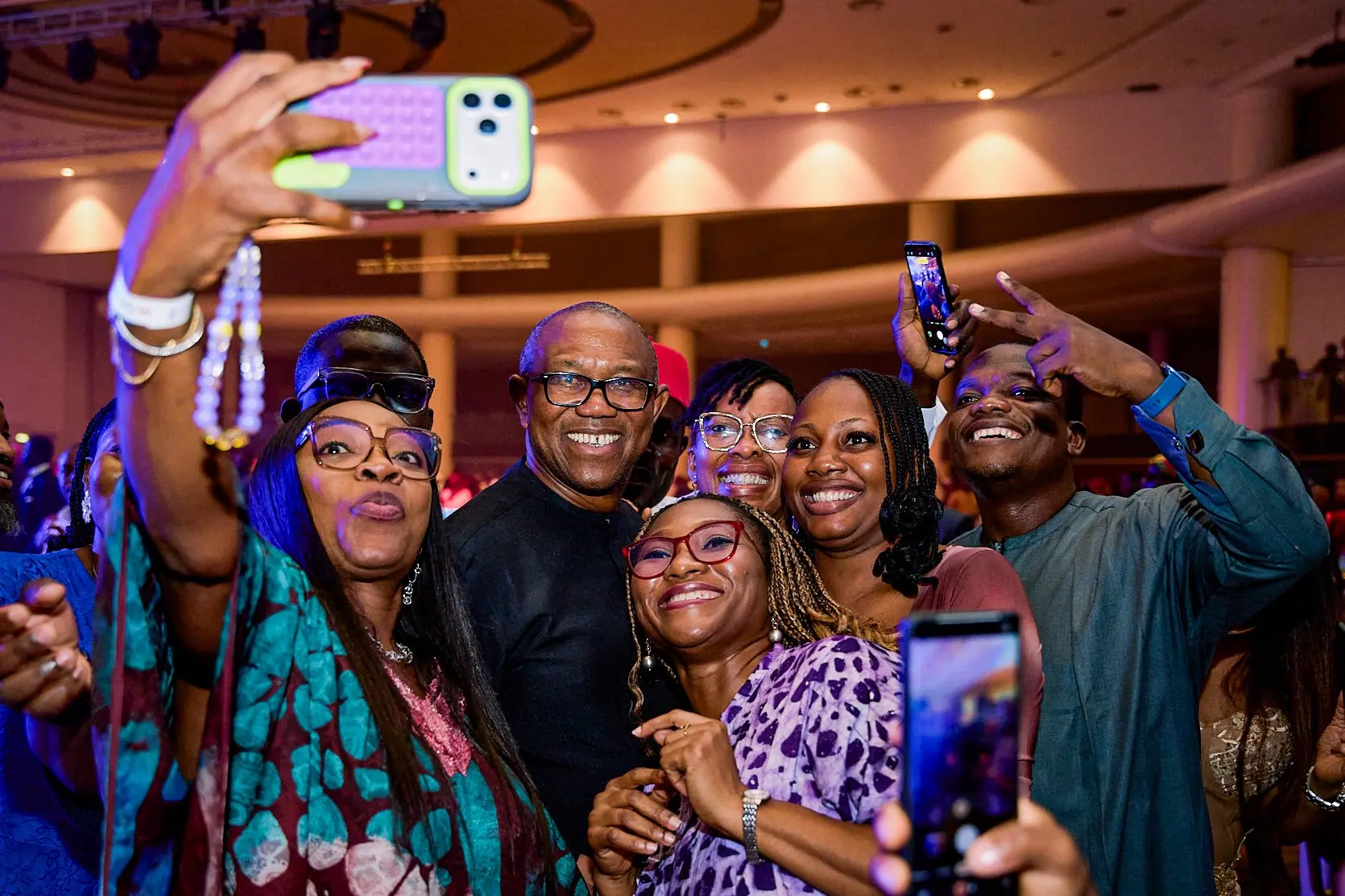 Peter Obi surrounded by guests taking selfies at an indoor reception