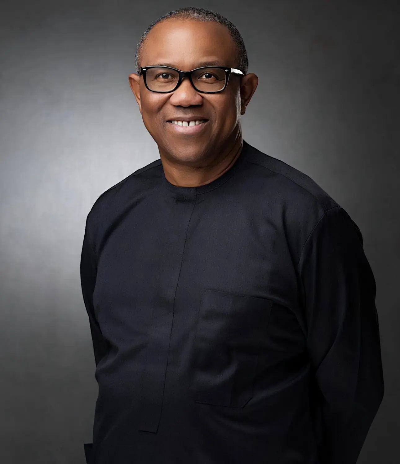 Peter Obi in a black tunic against a grey studio ground, turned slightly, smiling
