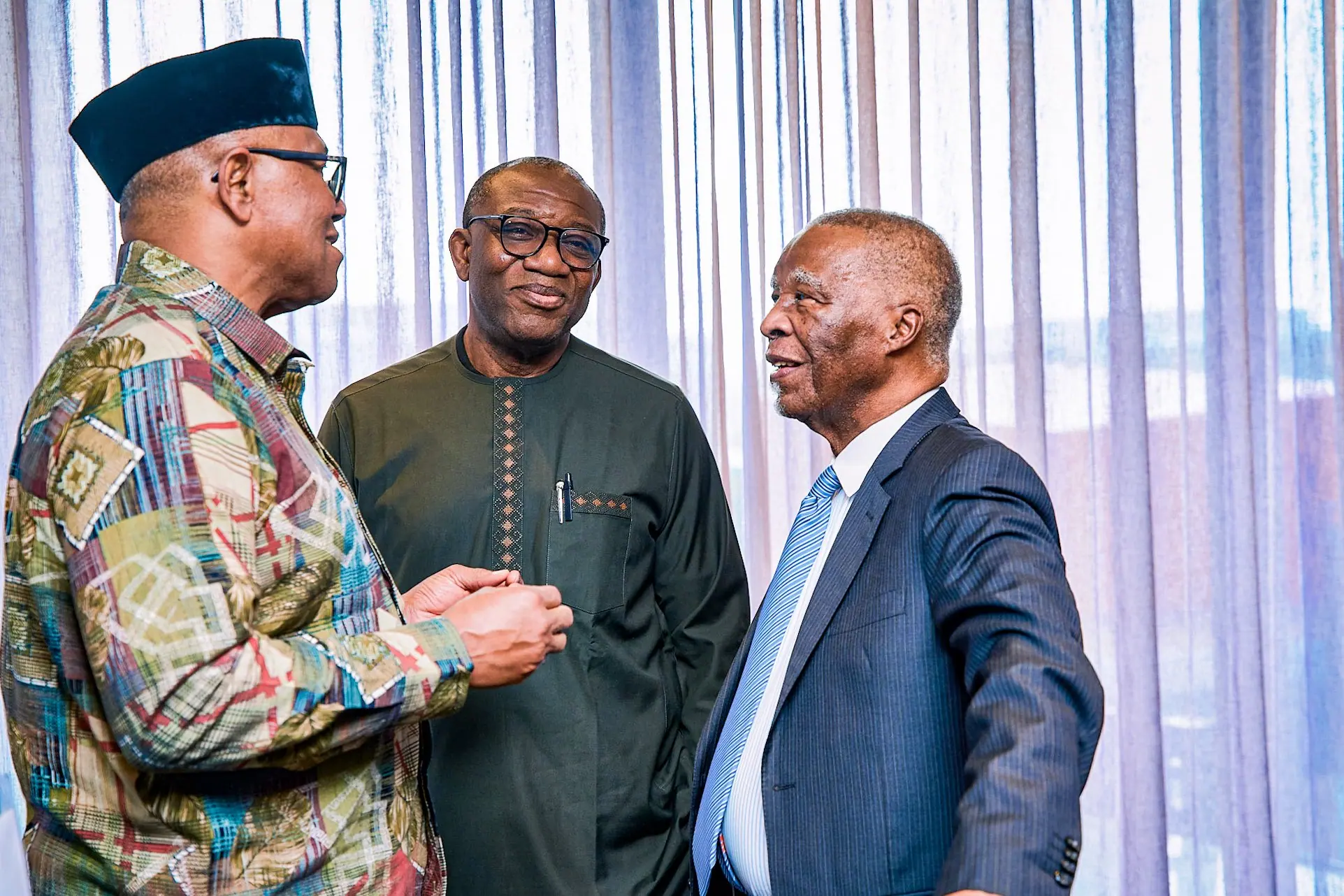 Peter Obi talking with two other men beside a window