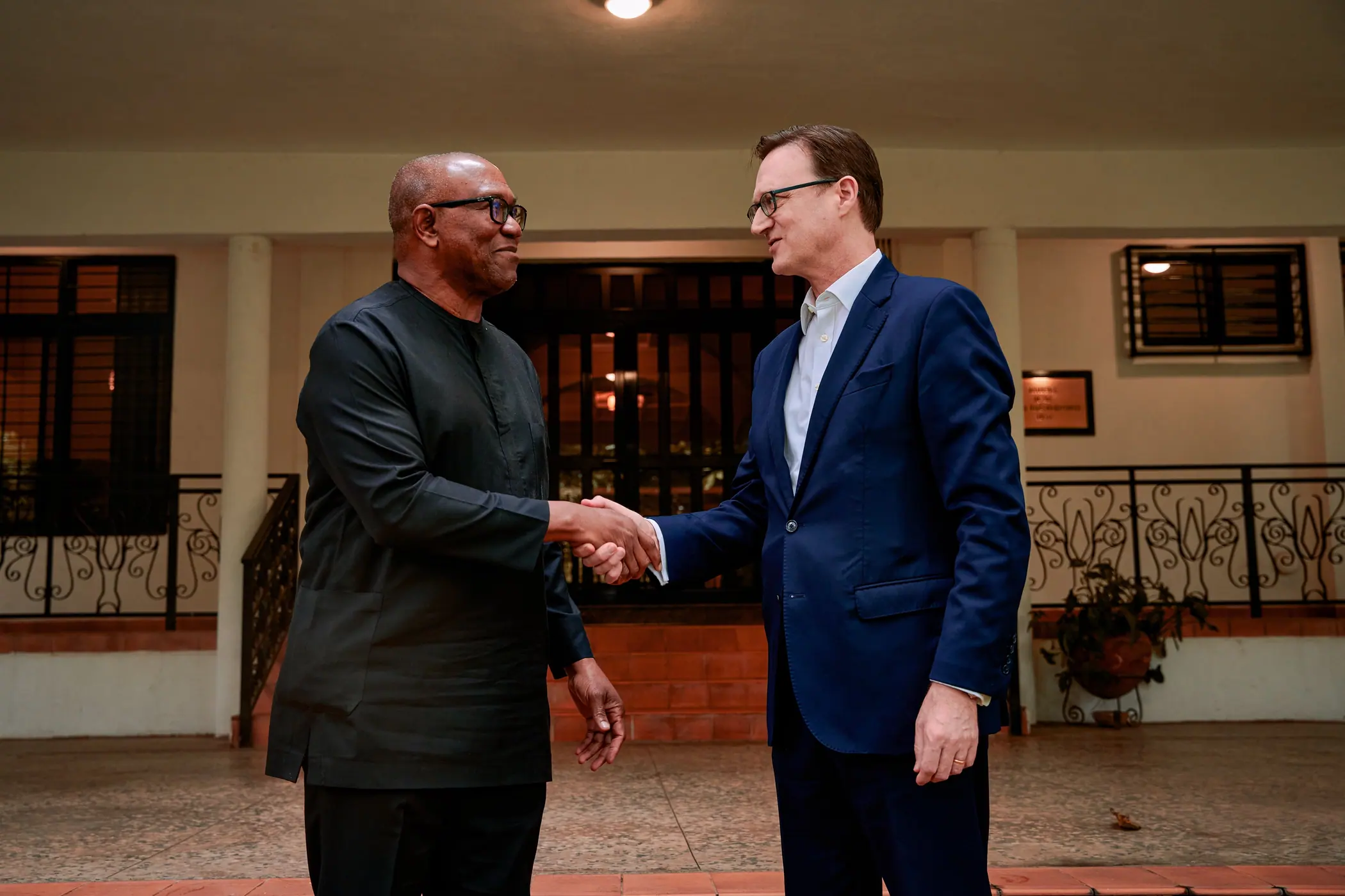 Peter Obi shaking hands with a visitor on a tiled veranda