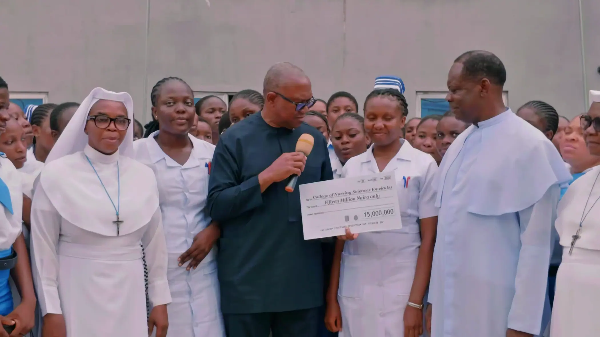 Peter Obi holding a presentation cheque with staff and students of a nursing college